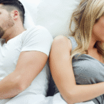 Casal deitado na cama de costas um para o outro demonstrando sinal de crise no casamento e afastamento.
